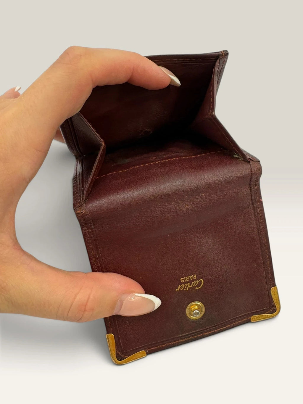 Cartier burgundy leather coin purse embossed logo with gold-tone corner hardware.