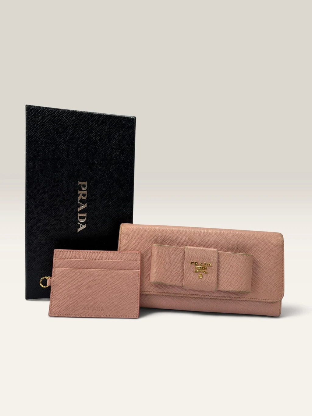 Prada pink leather wallet with structured bow detail and gold-tone hardware.