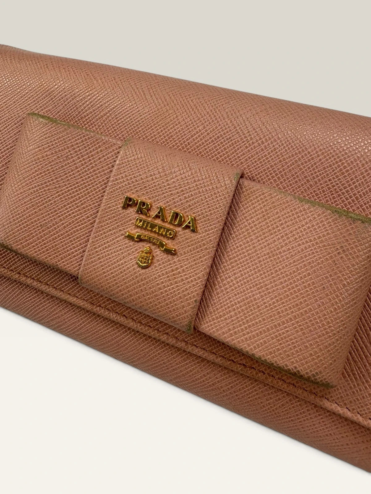 Prada pink leather wallet with structured bow detail and gold-tone hardware.