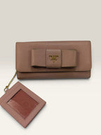 Prada pink leather wallet with structured bow detail and gold-tone hardware.