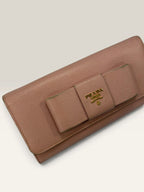 Prada pink leather wallet with structured bow detail and gold-tone hardware.