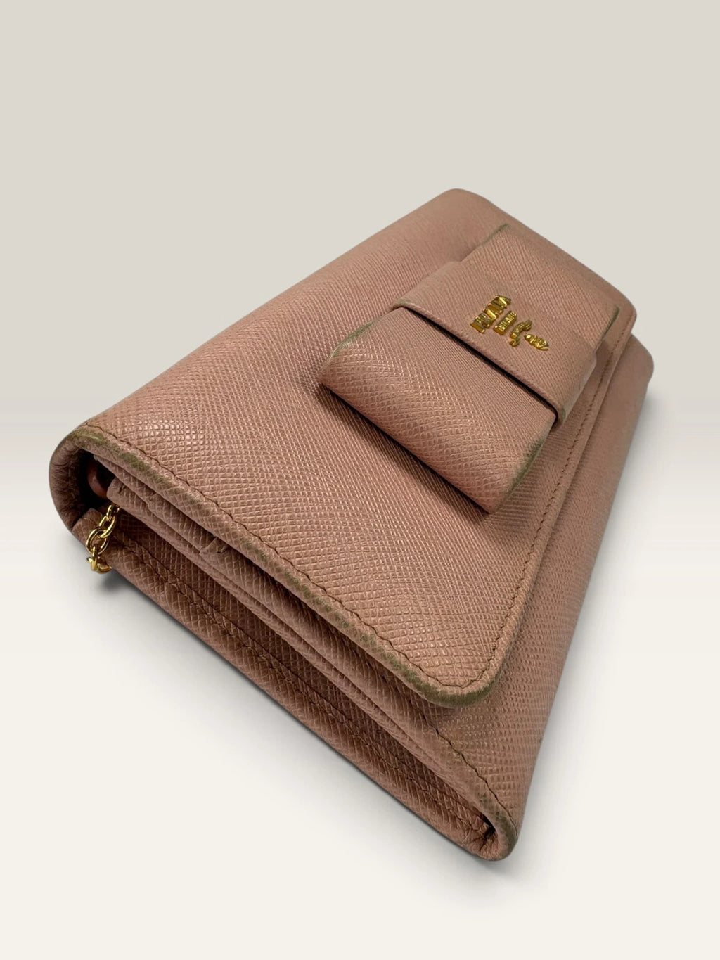 Prada pink leather wallet with structured bow detail and gold-tone hardware.