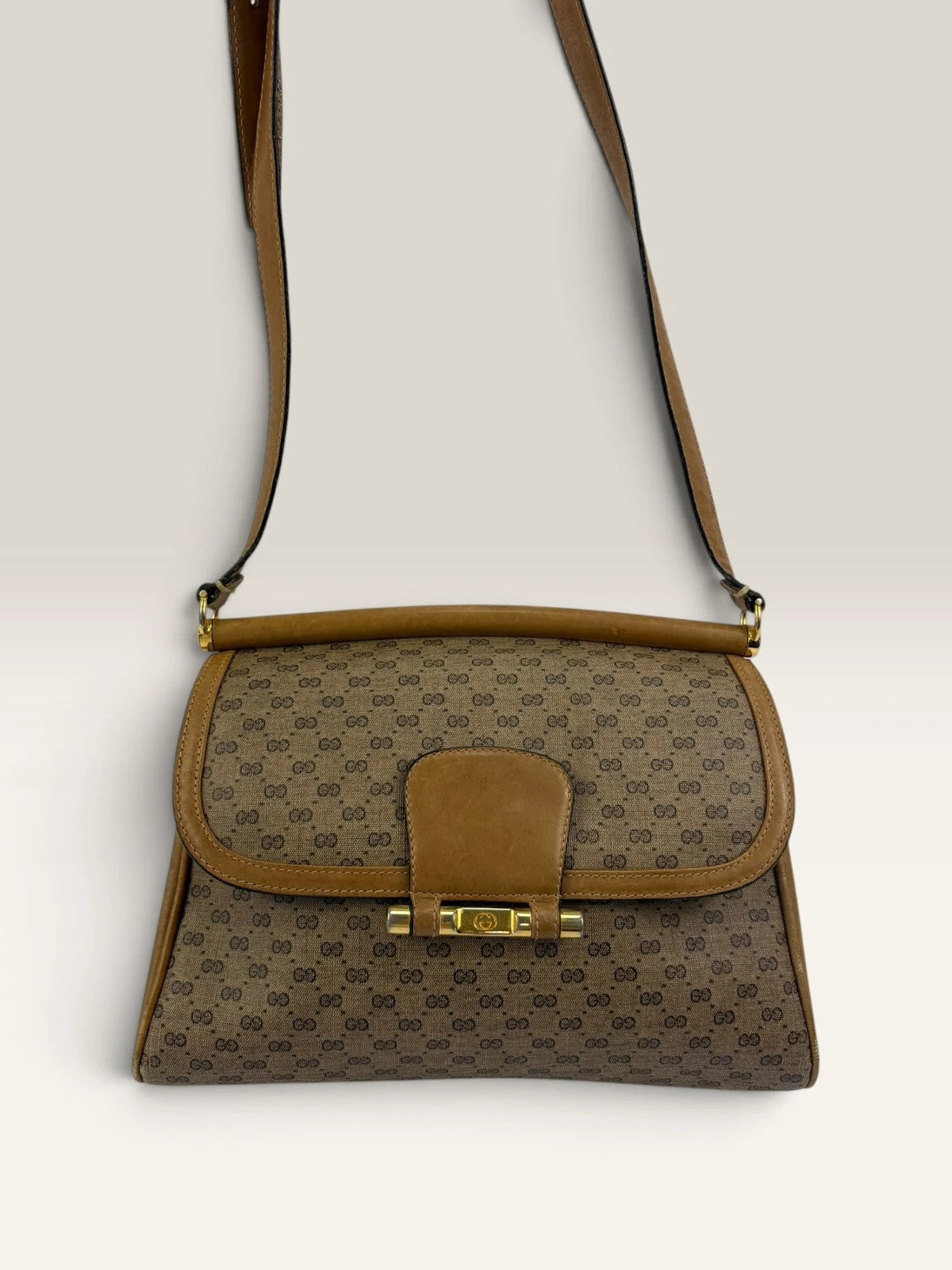 Gucci beige GG monogram canvas shoulder bag with brown leather trim and gold-tone hardware.