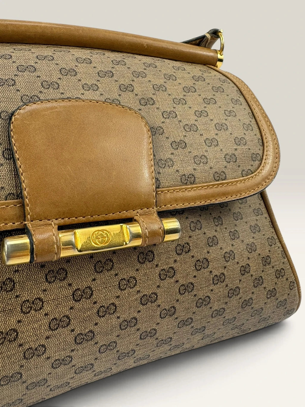 Gucci beige GG monogram canvas shoulder bag with brown leather trim and gold-tone hardware.