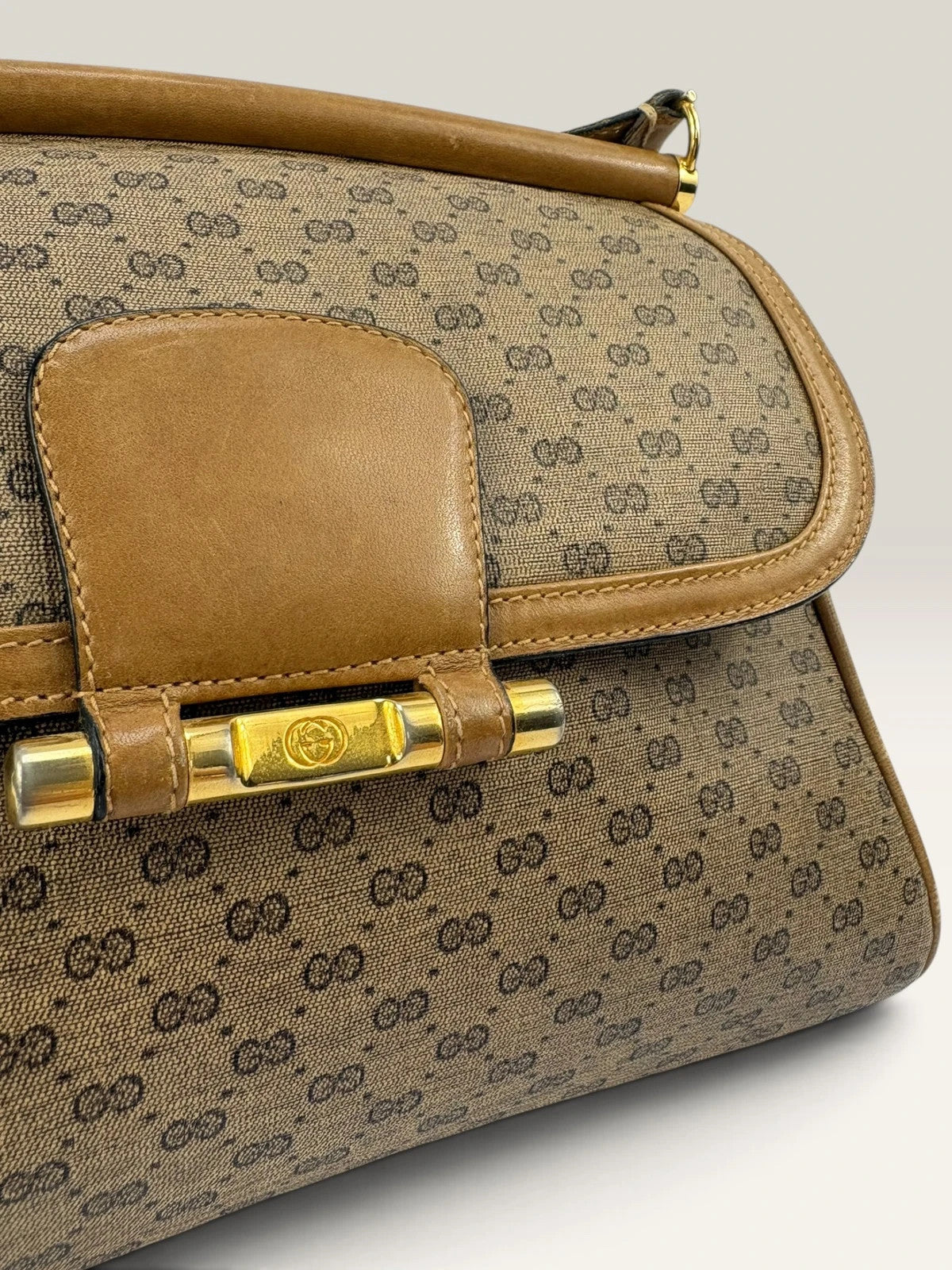 Gucci beige GG monogram canvas shoulder bag with brown leather trim and gold-tone hardware.