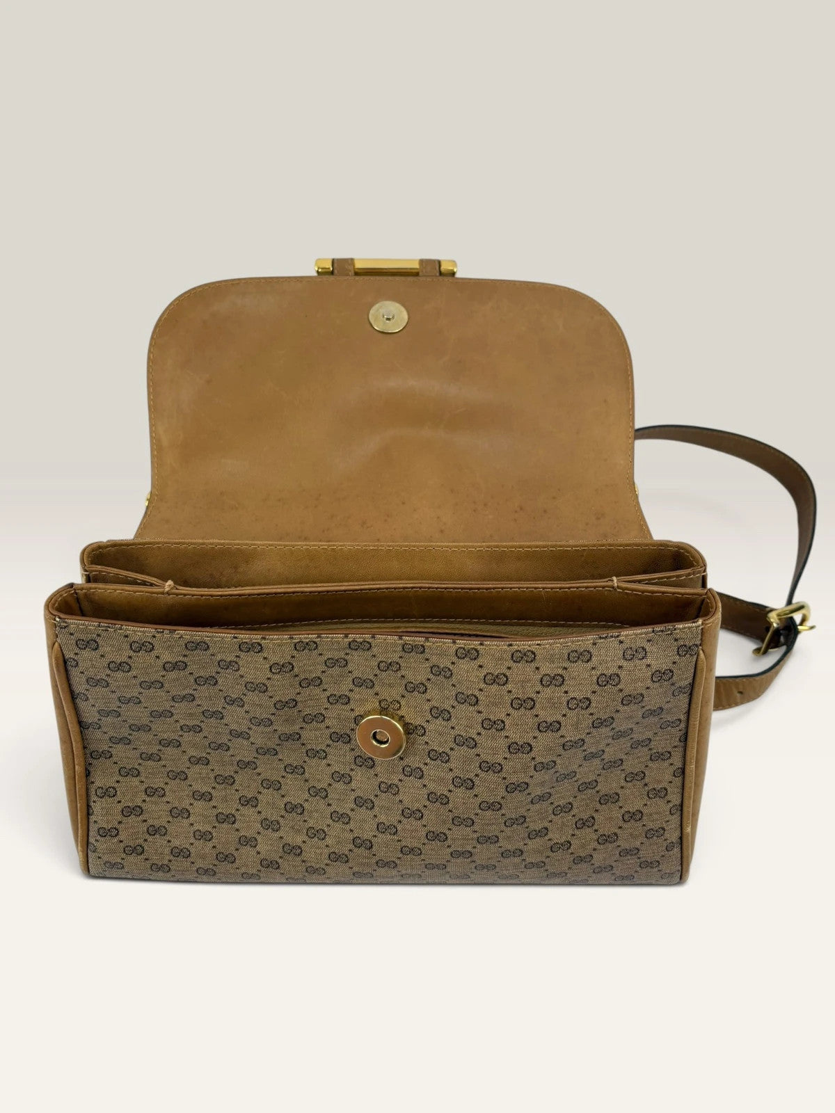 Gucci beige GG monogram canvas shoulder bag with brown leather trim and gold-tone hardware.