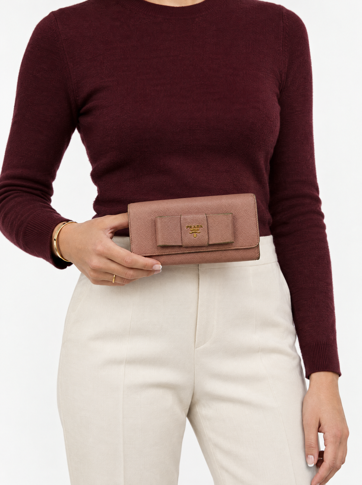 Styled photo of the Prada pink Saffiano bow wallet held by a model